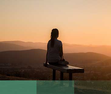 woman sitting on bench over viewing mountain